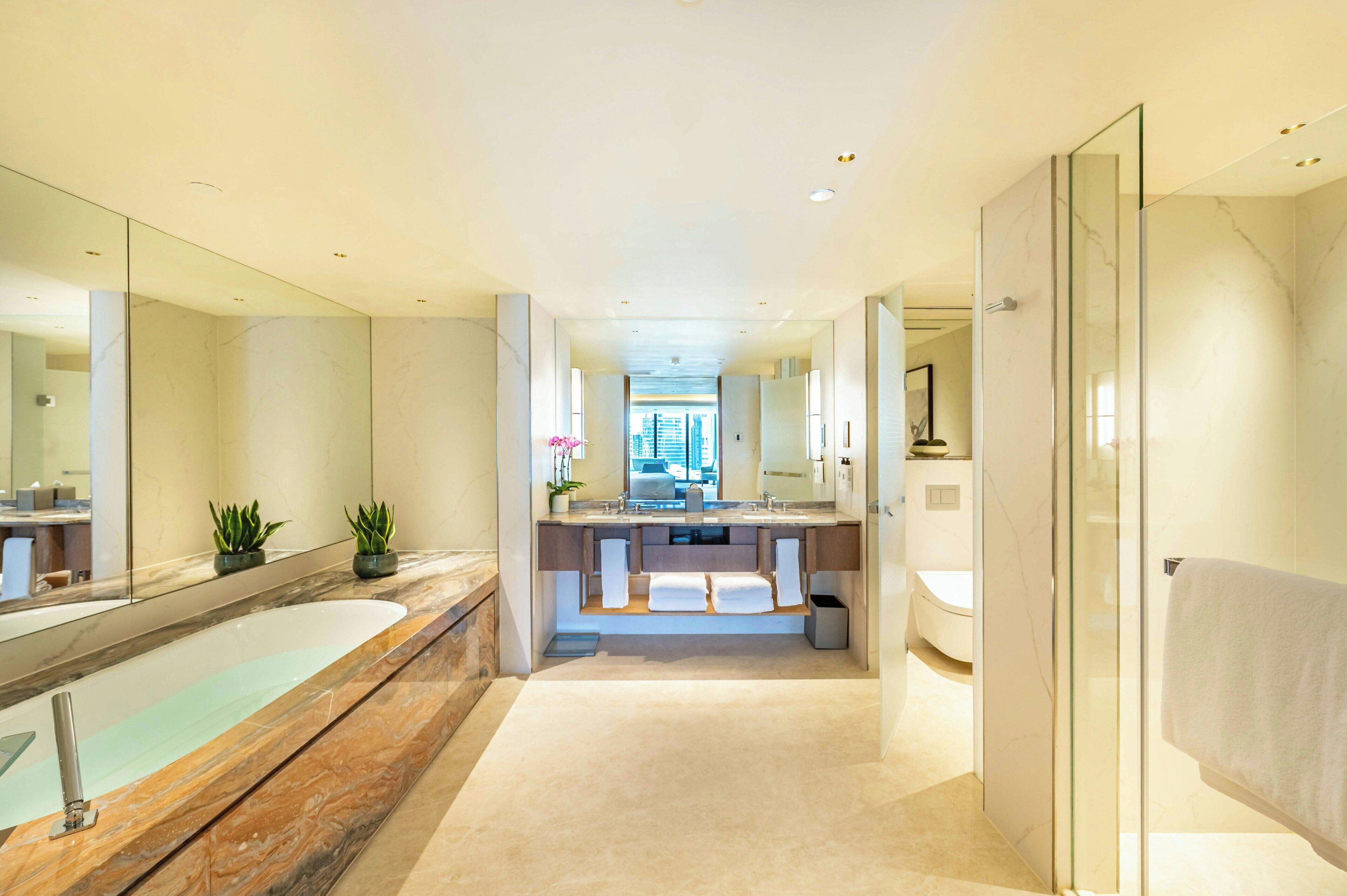 A modern bathroom with a large mirror, a bathtub, a shower, and a vanity with a sink.