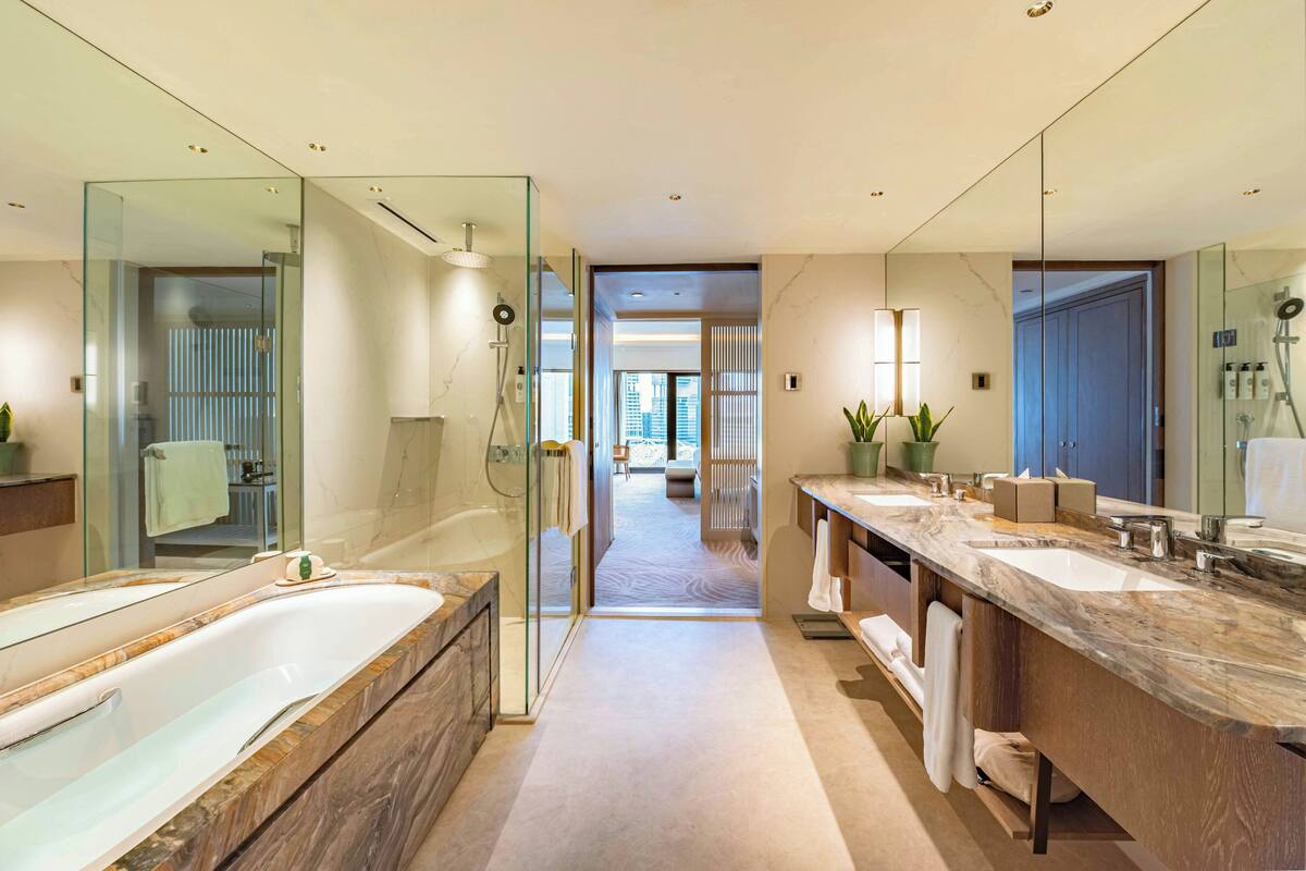 Un baño moderno con una bañera grande, una ducha a ras de suelo y un tocador con espejo.