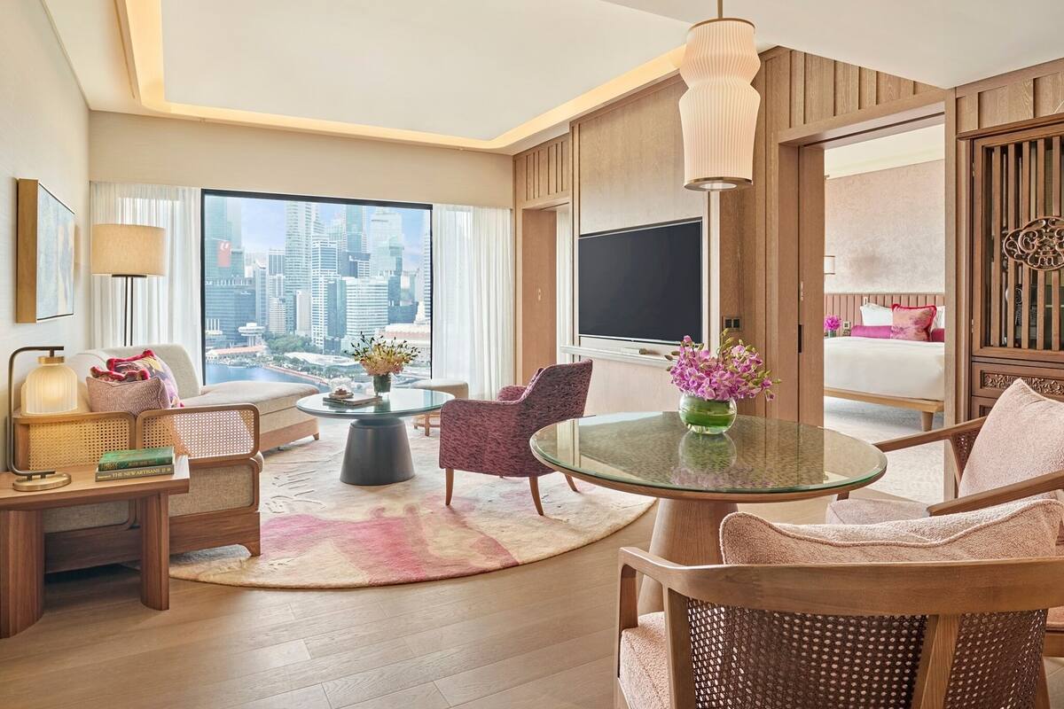 Een moderne hotelkamer met een groot raam dat uitzicht biedt op de stad, een ronde glazen tafel en een comfortabele zithoek.