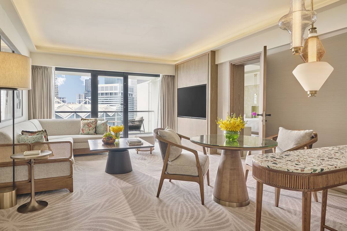 Een hotelkamer met balkon, een bank, een eettafel en een televisie.