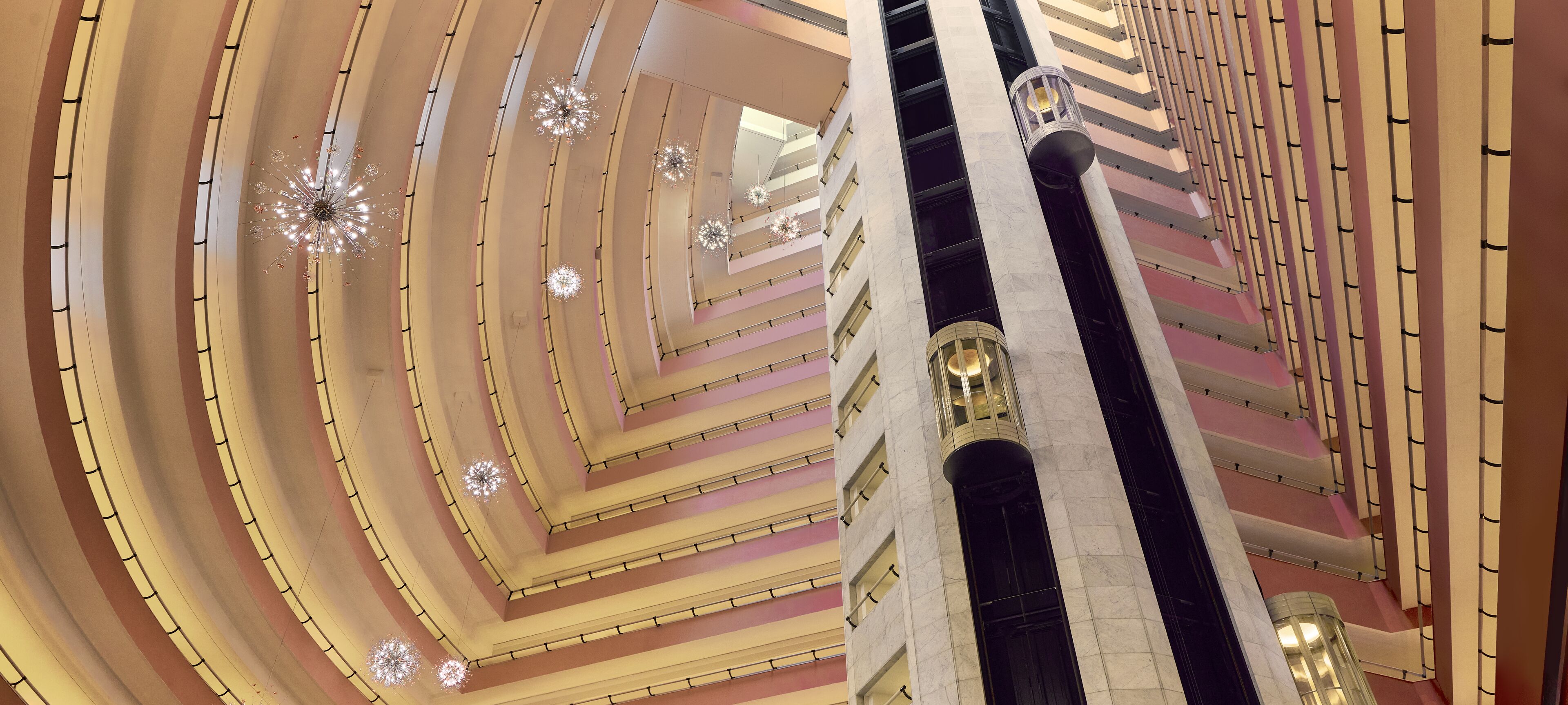A multi-level atrium with a central staircase, multiple floors, and decorative lighting fixtures.