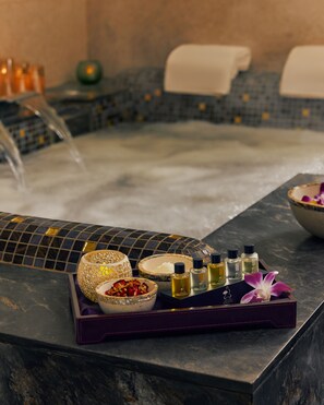 A spa area with a hot tub, a tray with bath products, and a bowl of dried flowers.