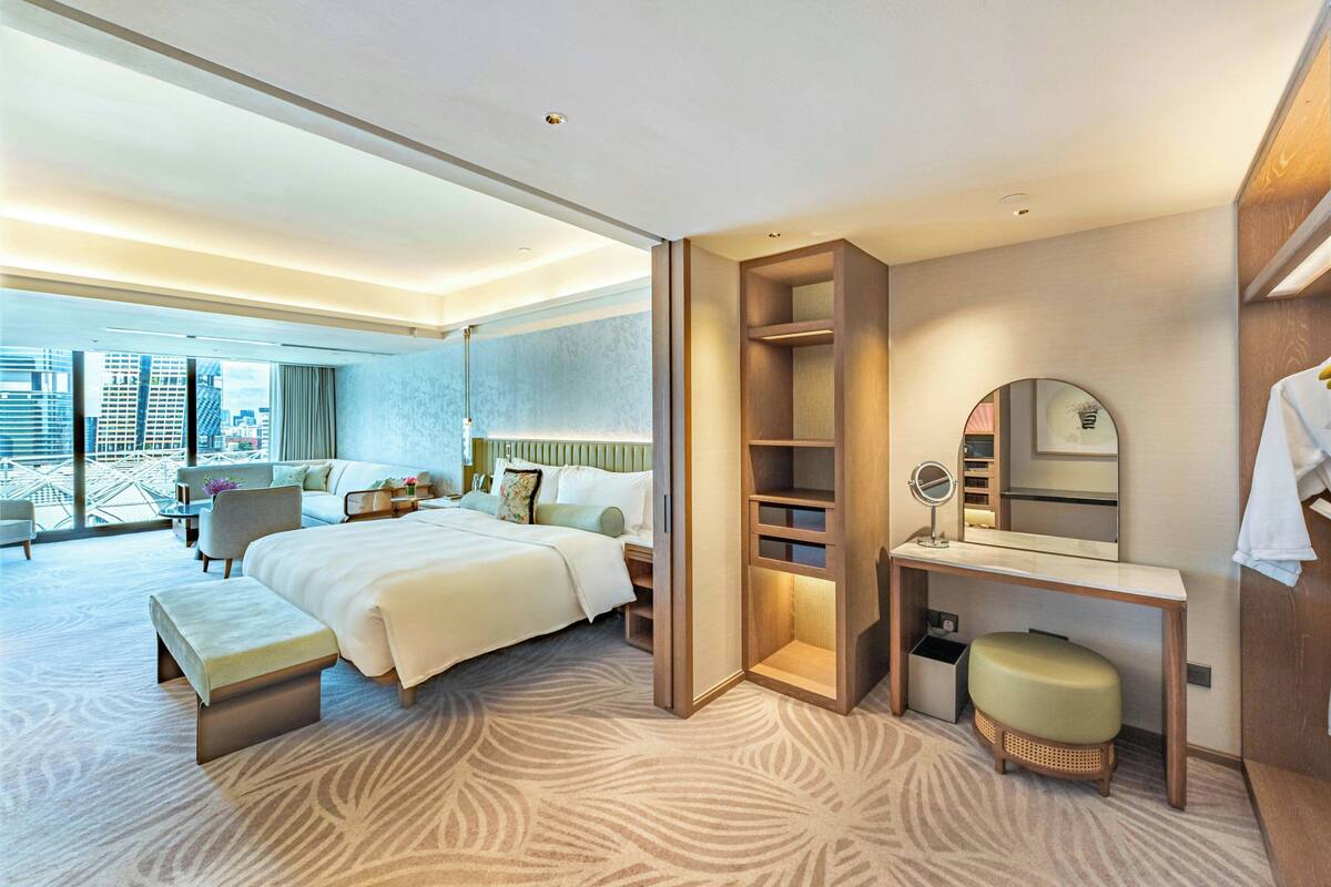 Habitación de hotel moderna con una cama grande, un escritorio con espejo y vistas a la ciudad.