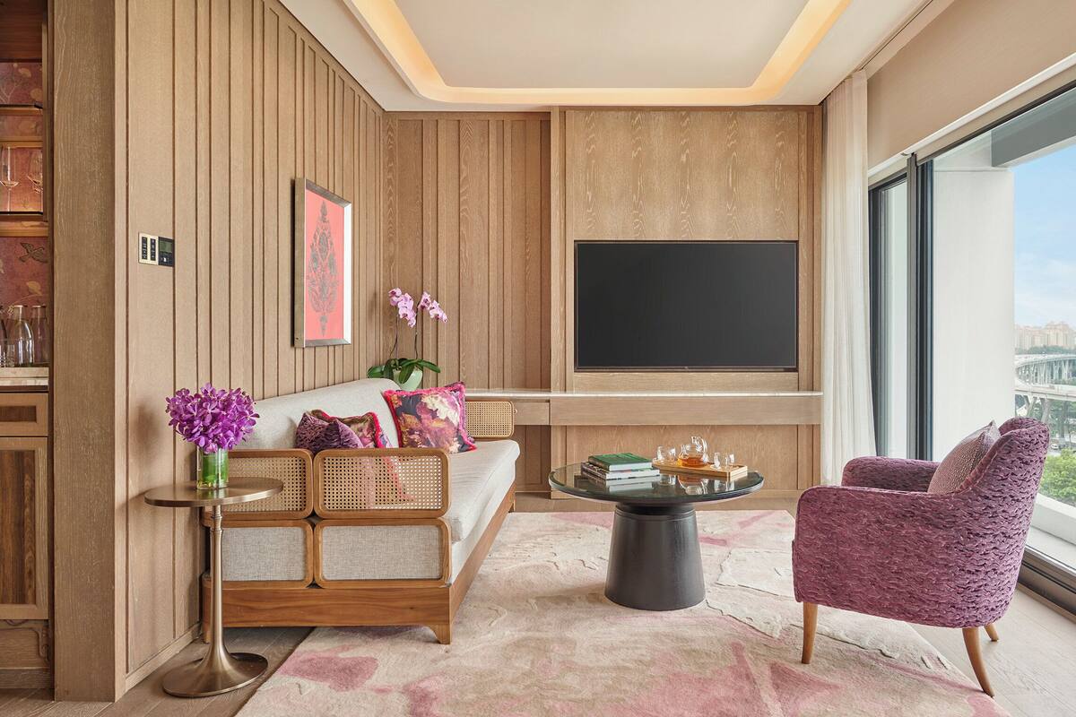 Een moderne woonkamer met een groot raam, een bank, een salontafel en een televisie.