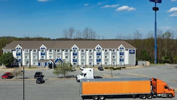 Un hôtel avec une rangée de chambres, un parking et un grand camion orange.
