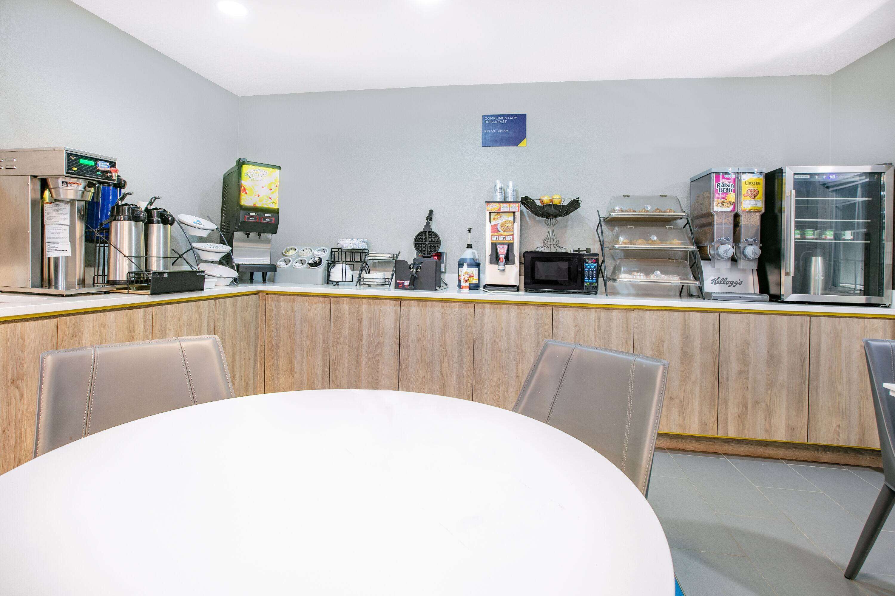 A modern hotel reception area with a counter, coffee machines, and seating.