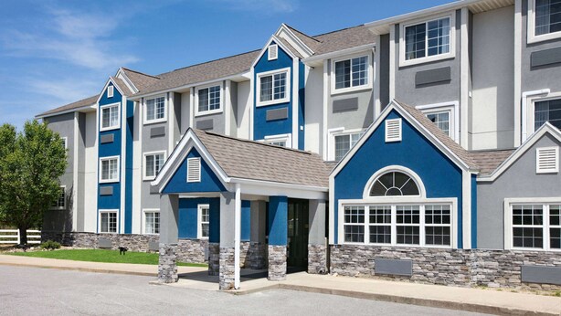 A multi-story residential building with a blue and gray exterior, stone accents, and a covered entryway. - Microtel Inn by Wyndham Beckley (Beckley)