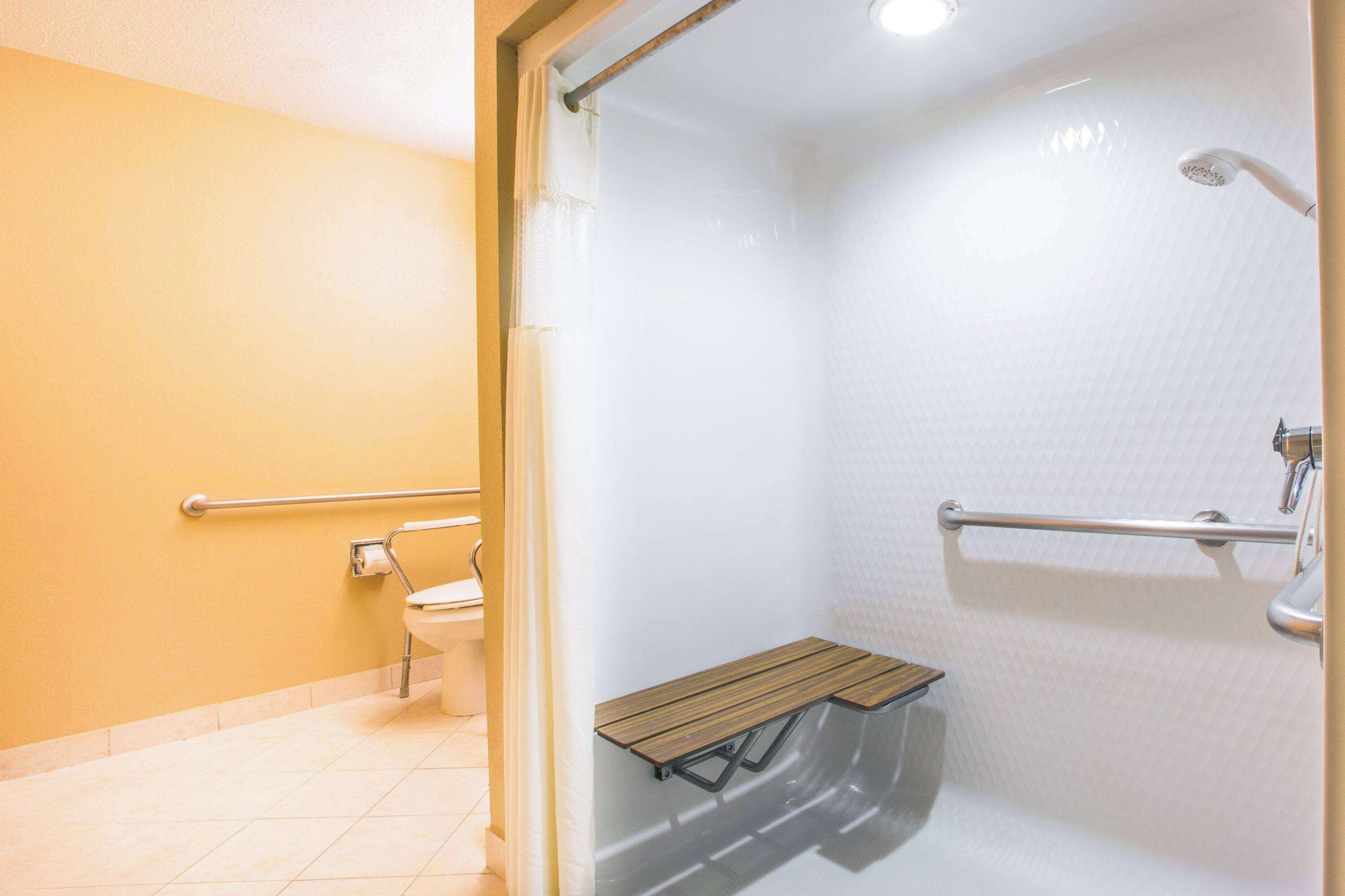 A bathroom with a shower, toilet, and bench.