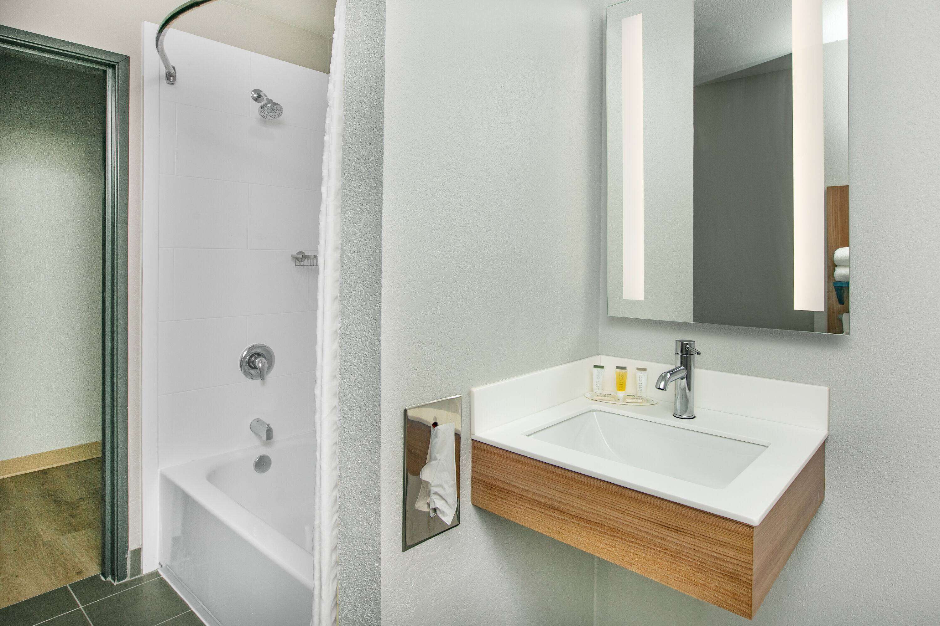A modern bathroom with a shower, a sink, and a mirror.