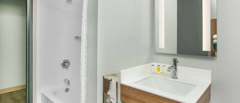 A modern bathroom with a shower, a sink, and a mirror.