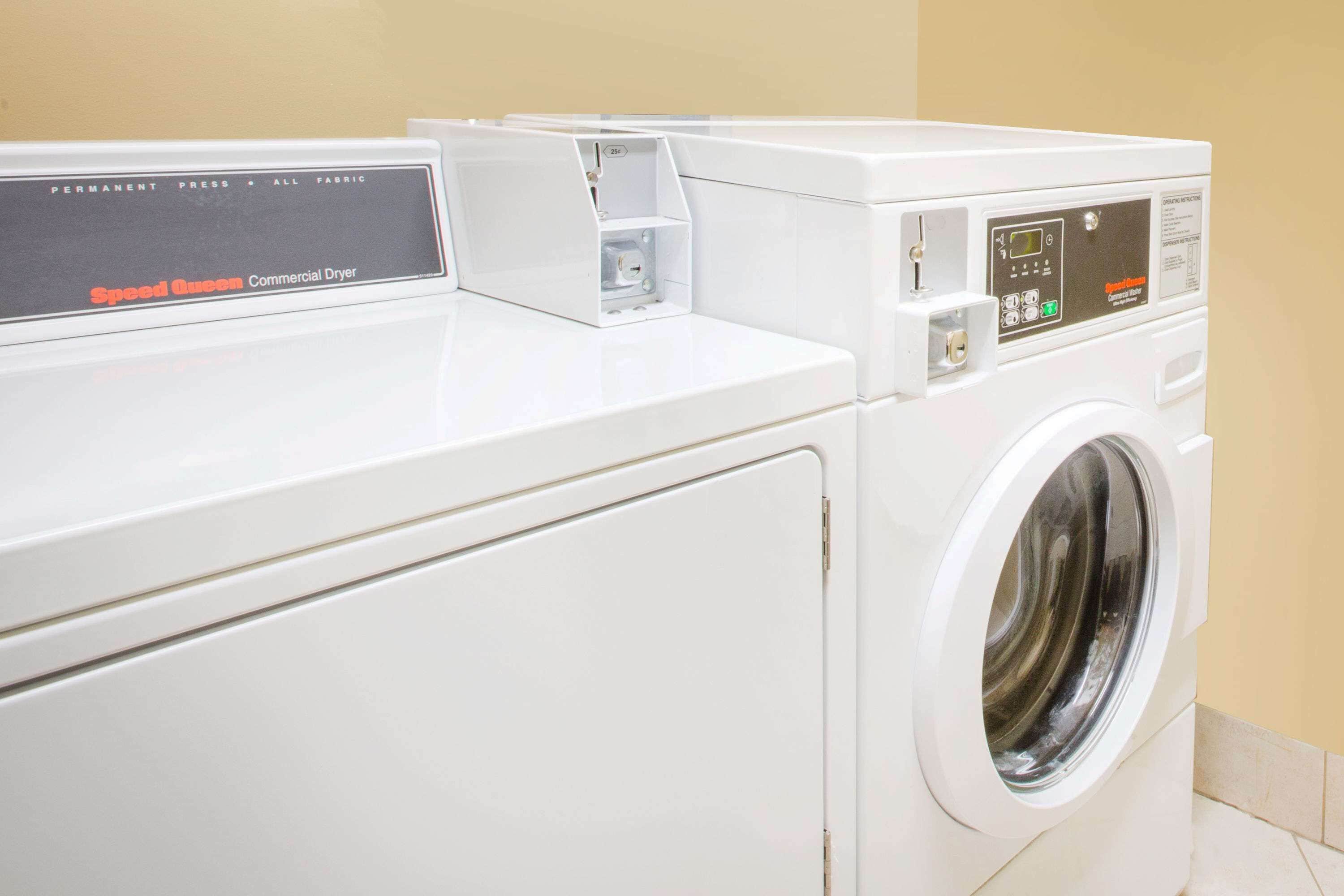 A row of white commercial dryers with control panels, labeled "Speed Queen."