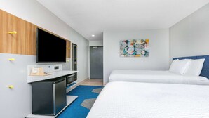 A hotel room with a bed, a desk with a flat-screen TV, a refrigerator, and a wall-mounted artwork. - Microtel Inn by Wyndham Beckley (Beckley)