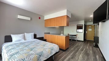 Ett hotellrum med en säng, ett litet kök, en matplats och en TV.