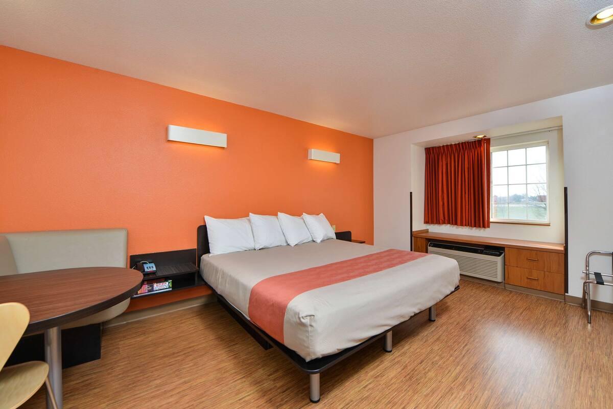 Ein Hotelzimmer mit Bett, Schreibtisch und einem fenster mit Vorhängen.