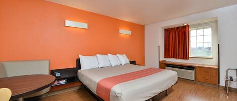 A hotel room with a bed, a desk, and a window with curtains.