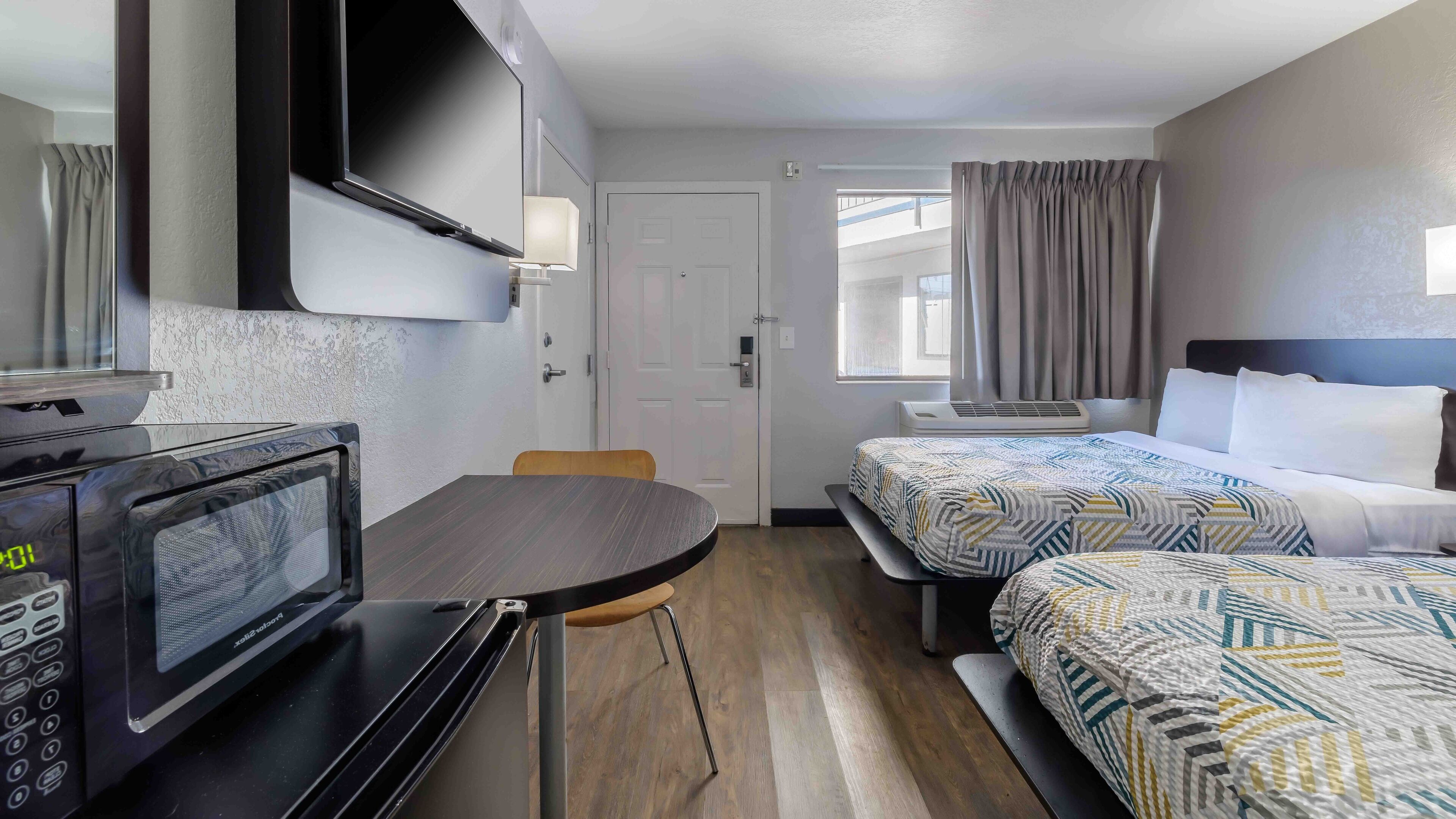 Une chambre d’hôtel équipée d’un lit, d’une table de chevet, d’un micro-ondes et d’un petit coin salon.