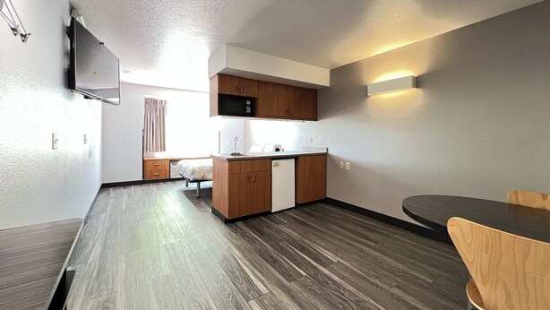 A compact kitchen with wooden cabinets, a microwave, and a built-in dishwasher.