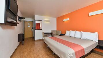 Habitación de hotel con cama, escritorio, silla y televisor.