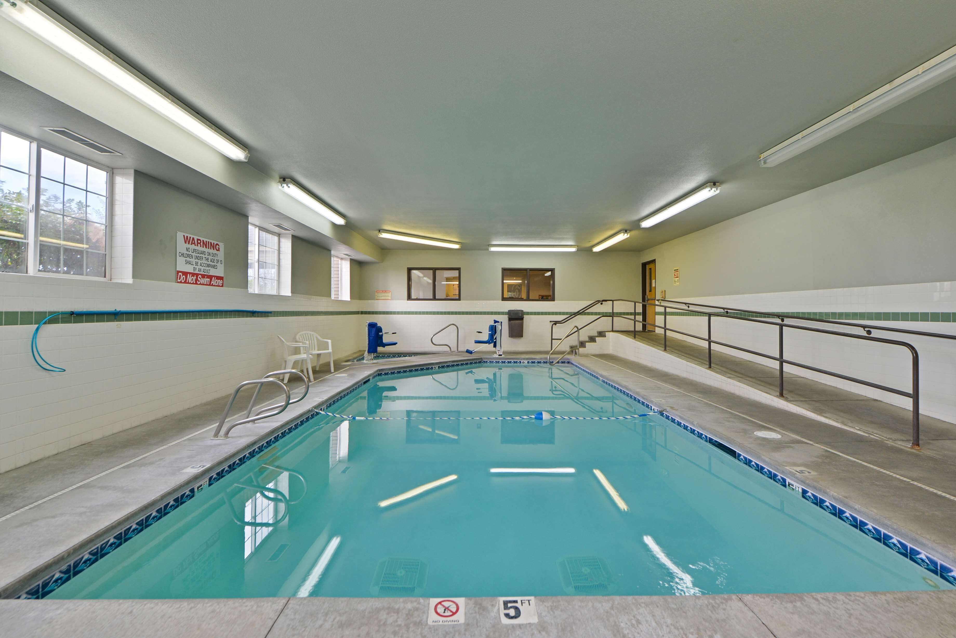 An indoor swimming pool with clear water, a no diving sign, and a 5 ft depth marker.