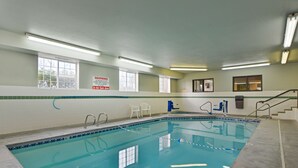 An indoor swimming pool with clear water, tiled walls, and a sign warning children to stay with an adult.
