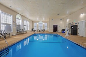 A large indoor swimming pool with a tiled floor, surrounded by chairs and tables, and large windows with arched tops. - Best Western Crown Inn & Suites (Batavia)