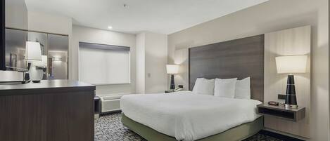 Una habitación de hotel con una cama grande, un escritorio, un espejo y una lámpara de pared.