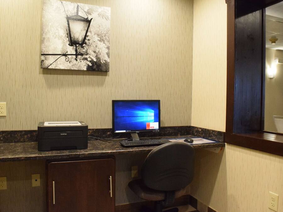 Una habitación de hotel con escritorio, computadora, impresora y una silla.