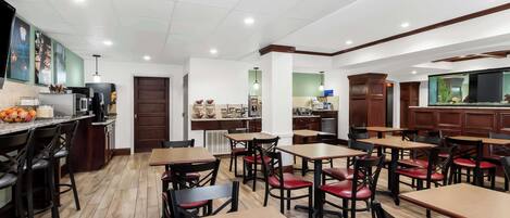 A restaurant with wooden tables and chairs, a kitchen area, and a fish tank.