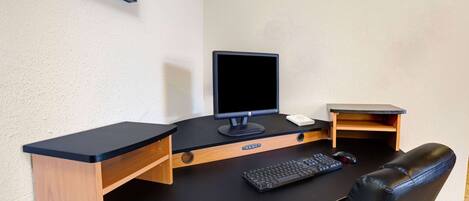 Un espacio de trabajo reducido con una computadora, teclado, ratón y una pequeña estantería.