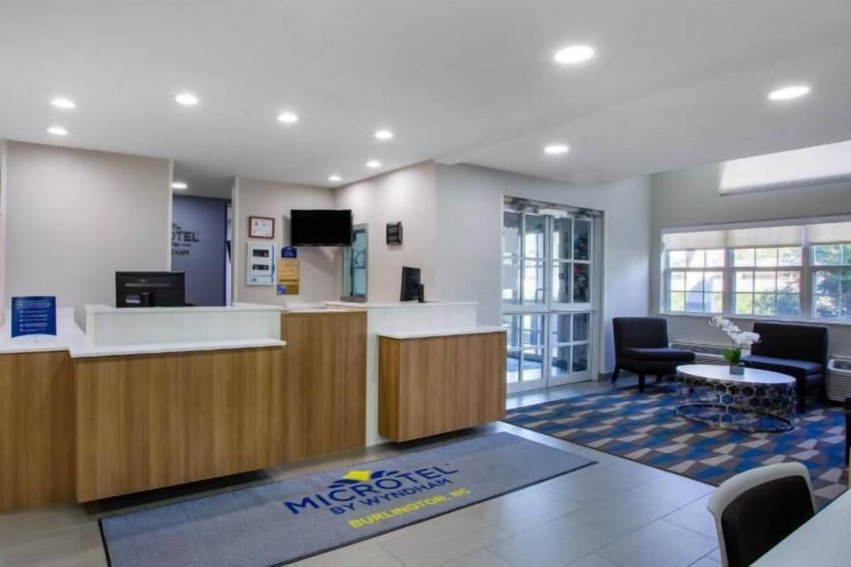 A reception area with a wooden reception desk, a flat-screen TV, and a seating area with a patterned rug.