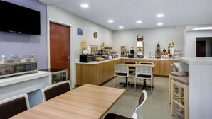 Una cocina moderna con mostrador de madera, sillas blancas y un televisor de pantalla plana montado en la pared.