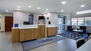 Zona de recepción de un hotel, con mostrador, asientos y grandes ventanales.