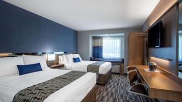 A hotel room with two beds, a desk, a TV, and a window with curtains.