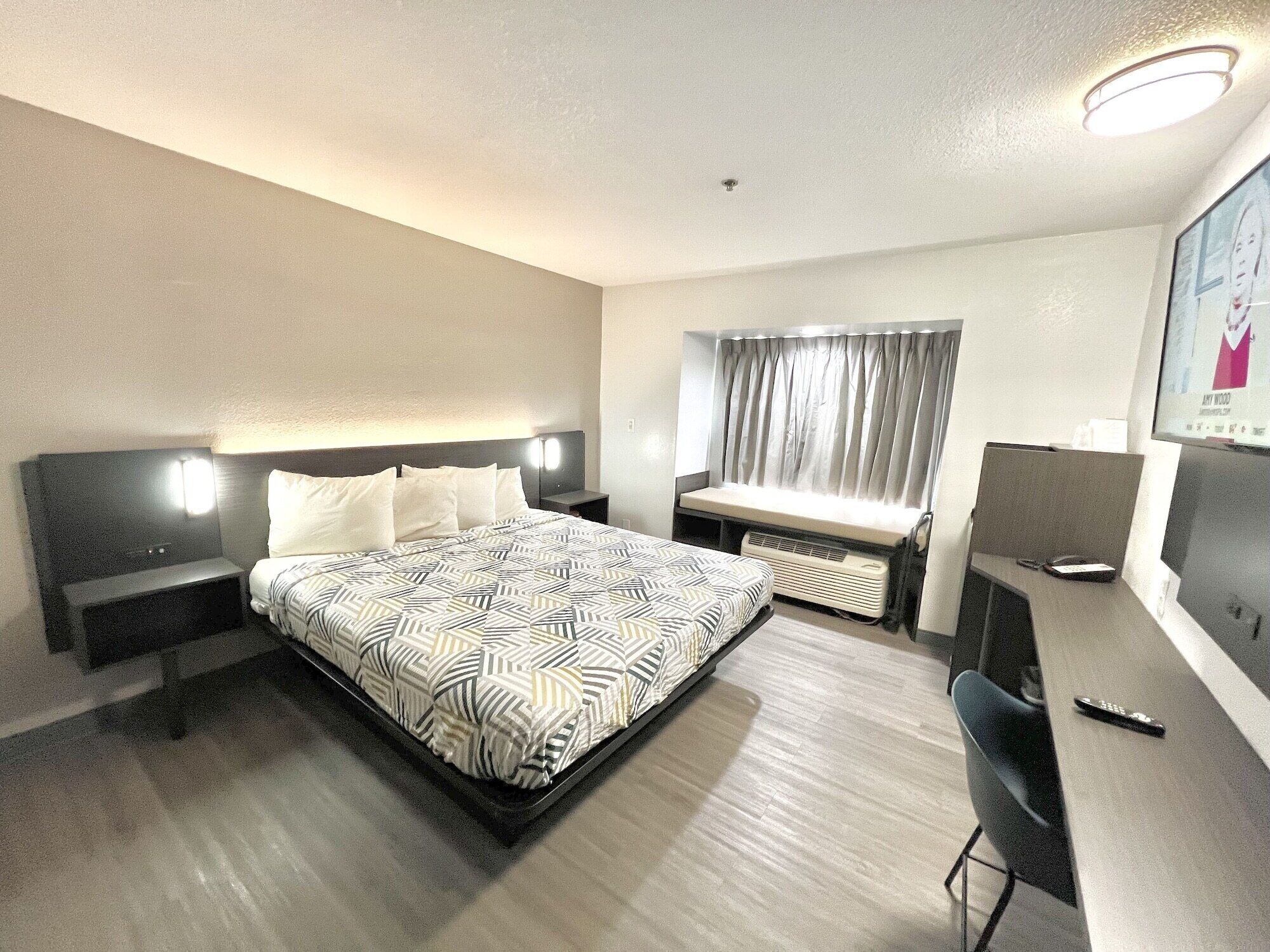 Una habitación de hotel con una cama, mesitas de noche, un escritorio y una silla.