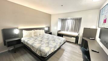 Una habitación de hotel con una cama, mesitas de noche, un escritorio y una silla.