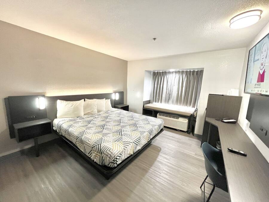 Una habitación de hotel con una cama, mesitas de noche, un escritorio y una silla.