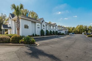 Guest rooms feature front porches with covered seating areas amidst well-manicured landscaping.