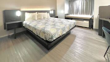 A modern hotel room with a large bed, bedside tables, a desk, and a window with curtains.