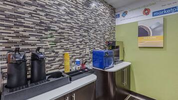 Un área de cocina moderna con salpicadero de azulejos, una cafetera y un microondas.