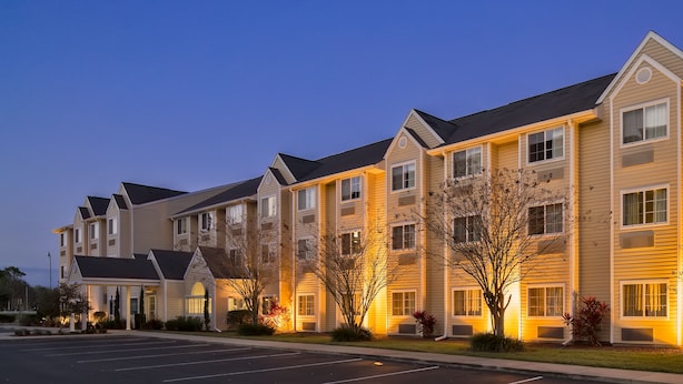 A multi-story hotel with a parking lot in front. - Microtel Inn & Suites by Wyndham Leesburg/Mt Dora (Leesburg)