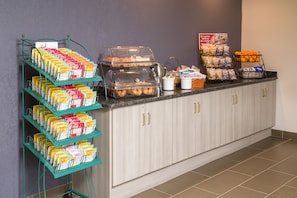 Uma área de buffet com diversos alimentos e um espaço para café à vontade.