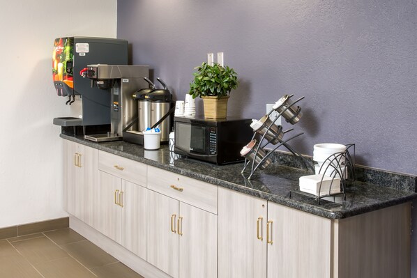 A modern kitchen with a coffee machine, microwave, and a plant on the counter. - Microtel Inn & Suites by Wyndham Leesburg/Mt Dora (Leesburg)