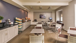 A modern dining area with a counter, seating, and a television. - Microtel Inn & Suites by Wyndham Leesburg/Mt Dora (Leesburg)