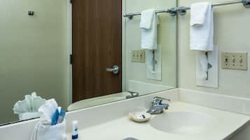 A bathroom with a white sink, a mirror, a towel rack with two white towels, and a tissue dispenser.