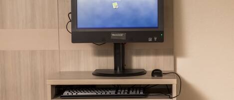 A Lenovo monitor on a wooden stand with a keyboard and mouse.