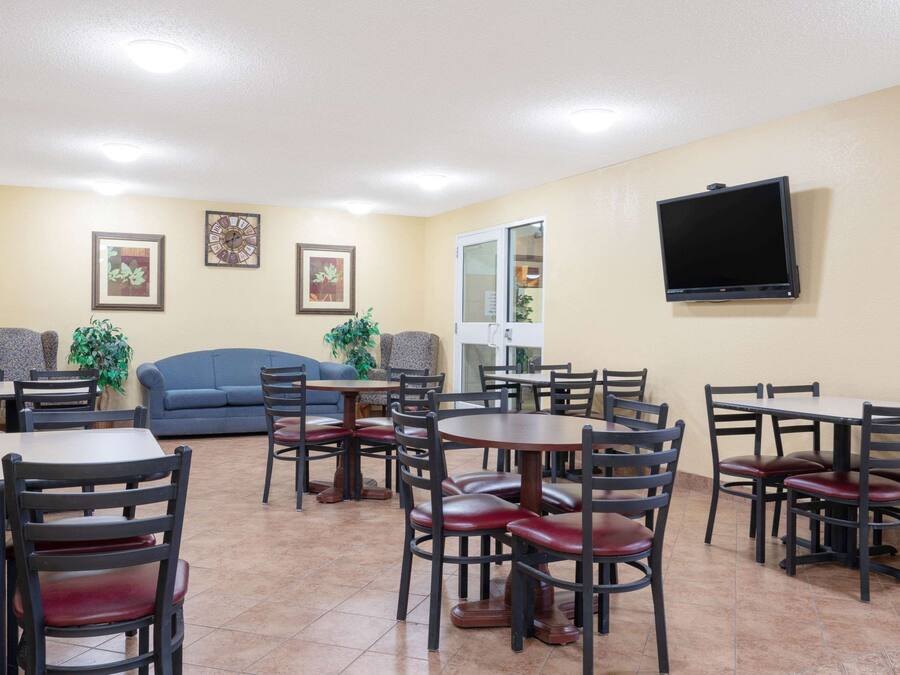 A dining area with multiple tables and chairs, a blue sofa, and a television mounted on the wall.