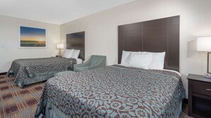 A hotel room with two beds, a chair, a nightstand, and a painting on the wall. - Days Inn by Wyndham Faribault (Faribault)