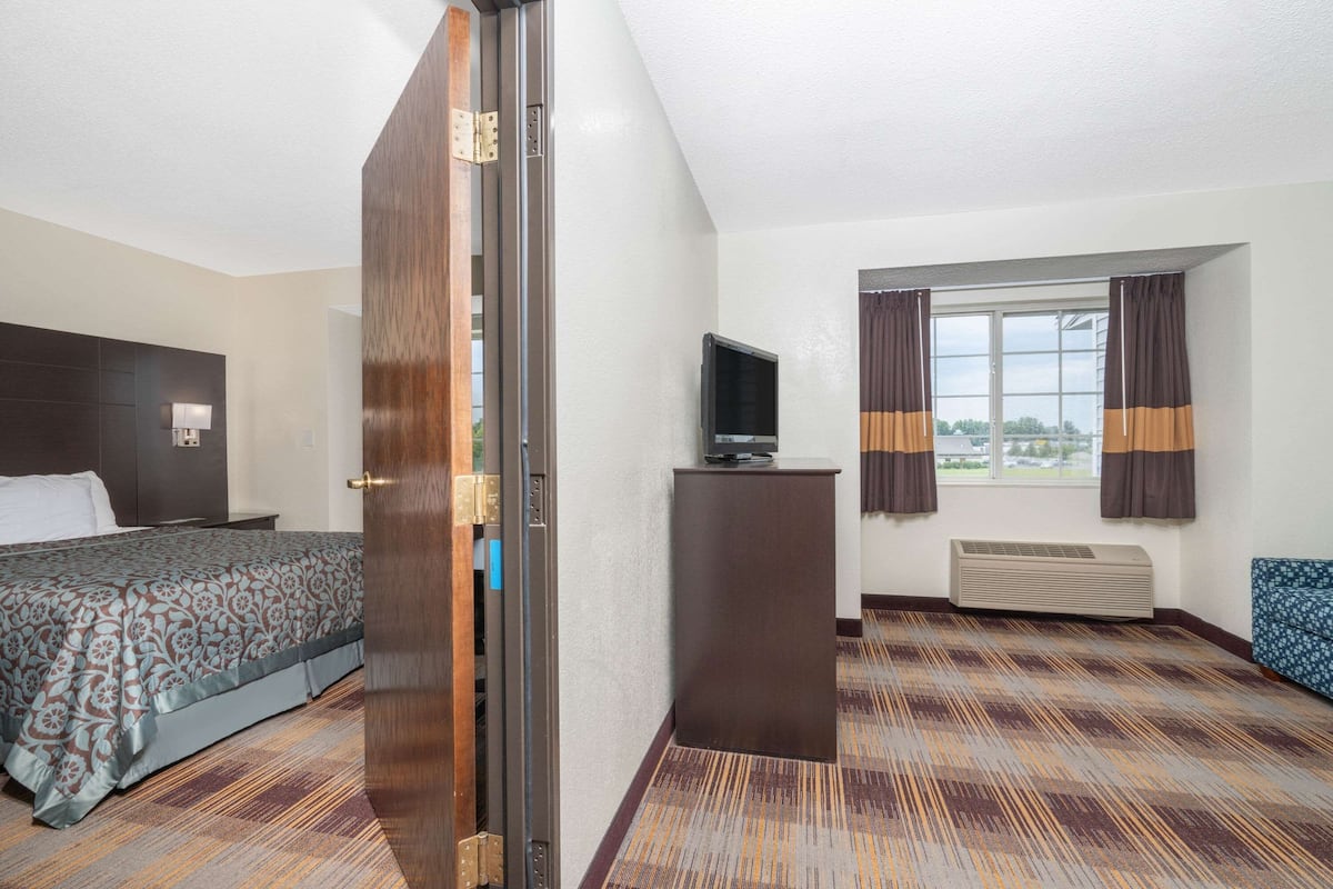 A hotel room with a bed, a desk, a television, and a window with curtains.