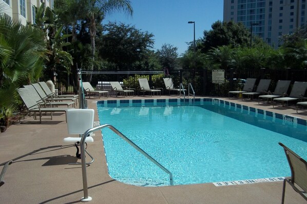 A swimming pool with lounge chairs and a lifeguard stand.