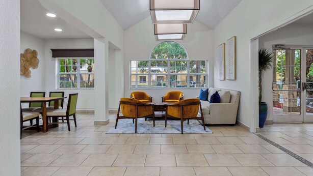 Amplia sala de estar con mesa de comedor, dos sillones, un sofá y un gran ventanal con vista a zonas verdes.